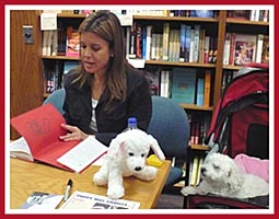 Jana Kolh signs a copy of A Rare Breed of Love as Baby the puppy mill survivor watches.