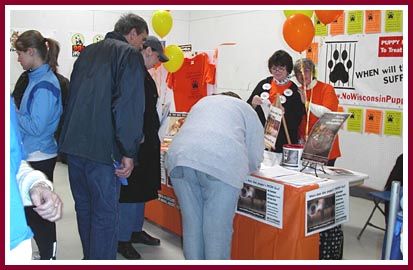 Visitors to the WPMP table at the Oshkosh Pet Expo take the time to sigh the No Wisconsin Puppy Mills petition.